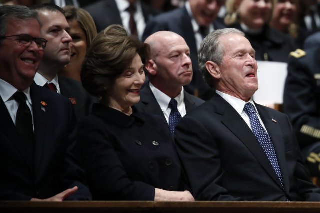 조지 W 부시 전 미국 대통령(오른쪽)과 부인 로라 여사, 젭 부시(왼쪽)가 5일(현지시간) 워싱턴DC 국립성당에서 열린 조지 H W 부시 전대통령 장례식 중 조사를 들으며 웃고 있다. ﻿【 워싱턴=AP/뉴시스】
