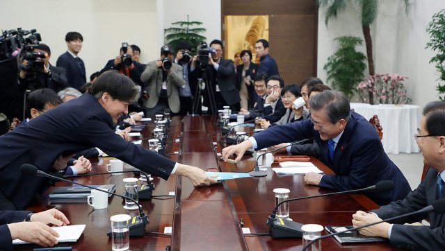 문재인 대통령이 22일 청와대 여민관에서 열린 수석·보좌관 회의에서 모두발언을 마친 후 조국 민정수석으로부터 과자를 받고 있다. (청와대 제공) 2018.1.22/뉴스1 © News1