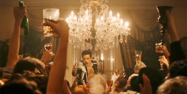 영화 ‘보헤미안 랩소디’에서 록밴드 ‘퀸’의 메인보컬 프레디 머큐리(라미 말렉·가운데)가 자신의 집에 초대한 사람들 앞에서 술잔을 들고 있다. 영화 ‘보헤미안 랩소디’ 예고편 캡처