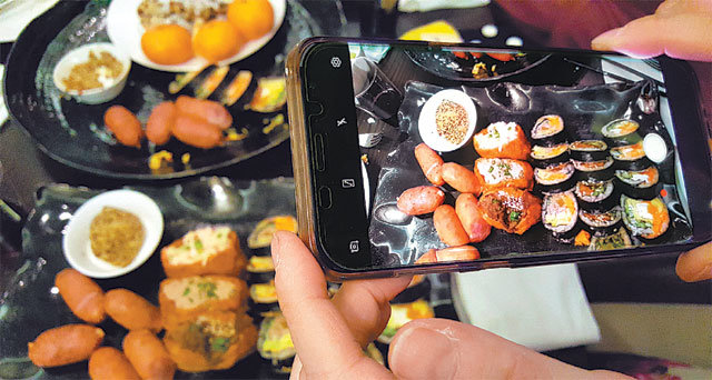 연말 모임에 참석한 한 시민이 스마트폰 카메라로 음식을 촬영하고 있다. 잘 찍은 사진을 SNS에 올려 공유하는 먹스타그램은 스마트폰 카메라가 만들어낸 또 하나의 문화이다.