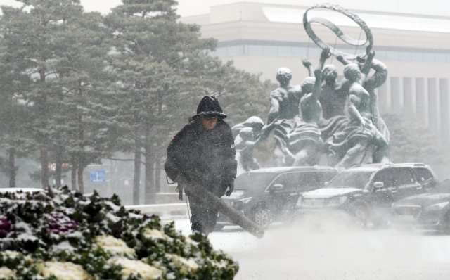 13일 오전 눈이 내린 서울 여의도 국회에서 직원이 장비를 이용해 눈을 치우고 있다. © News1