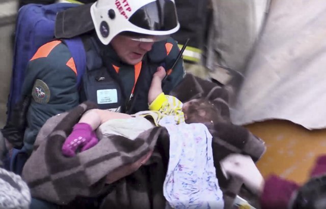 러시아 우랄산맥 인근 마그니토고로스크에 위치한 아파트 붕괴사고 현장에서 1일(현지시간) 구조대원들이 11개월된 남자아기를 사고현장에서 구조하고 있다.【마그니토고르스크(첼라빈스크)=AP/뉴시스】