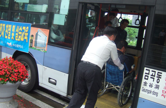 저상버스 앱을 통해 서비스 이용 문자 연락을 받은 시내버스 운전사가 휠체어를 탄 장애인 교통약자에게 탑승 서비스를 시행하고 있다. 부산시 제공