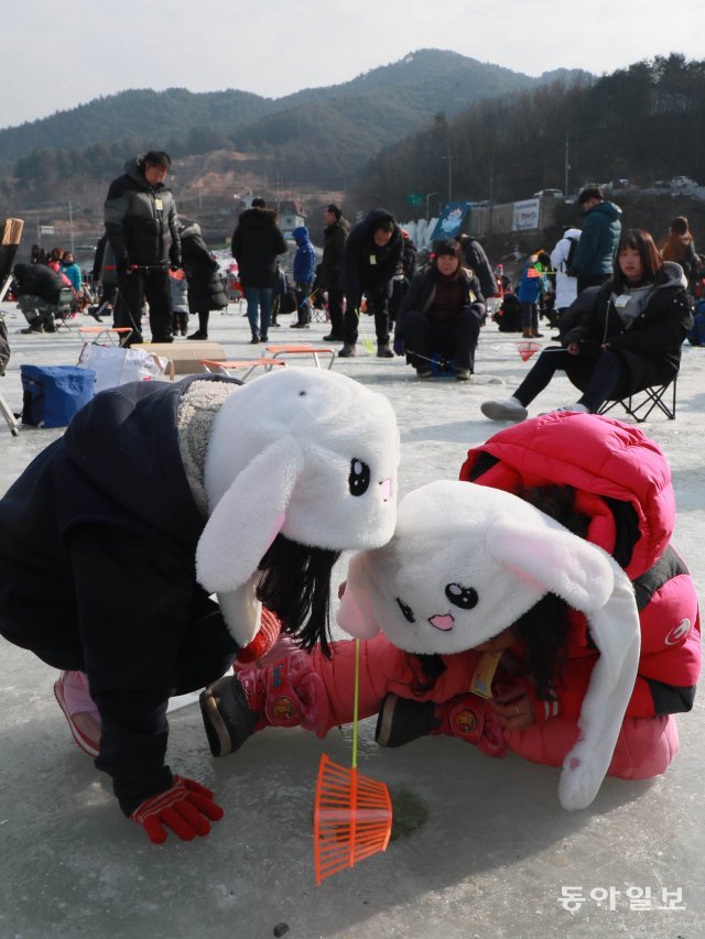 송어잡는 토끼 자매?  귀 쫑긋 토끼 모자를 쓴 어린이들이 얼음낚시를 하고 있다.