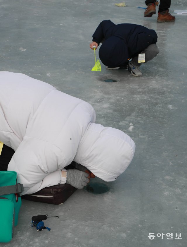 자세히 보아야 보인다.  관광객이 얼음낚시 구멍을 직접 쳐다보며 낚시를 하고 있다.