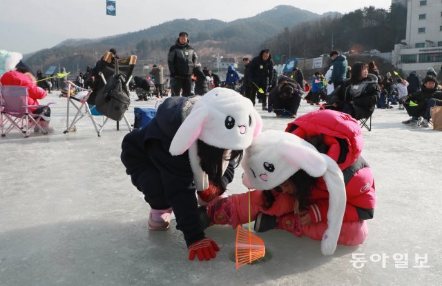 송어잡는 토끼 자매?  귀 쫑긋 토끼 모자를 쓴 어린이들이 얼음낚시를 하고 있다.