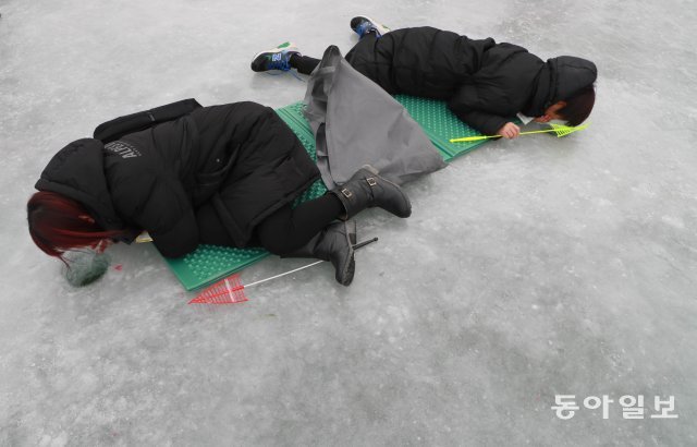 자세히 보아야 보인다.  관광객이 얼음낚시 구멍을 직접 쳐다보며 낚시를 하고 있다.