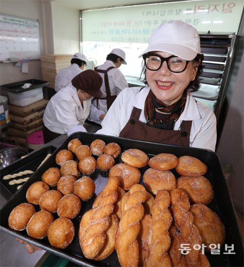 15일 오후 서울 은평구 꽈배기나라에서 점장 안국희 씨가 갓 구워낸 꽈배기와 찹쌀 도넛을 들고 미소 짓고 있다. 이곳에서 꽈배기와 도넛을 만드는 6명은 모두 70세가 넘은 어르신들이다. 김동주 기자 zoo@donga.com