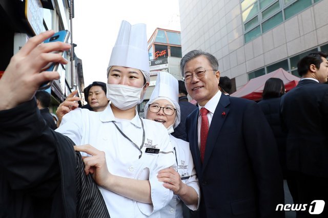 문재인 대통령이 24일 오후 대전의 빵집 성심당을 찾아 직원들가 ‘셀카’를 찍고 있다. (청와대 제공)