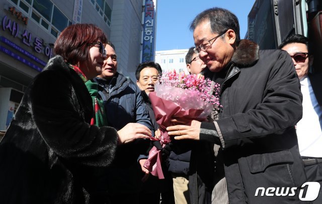 홍준표 자유한국당 전 대표가 26일 오후 부산 자갈치 시장에서 지지자에게 꽃다발을 받으며 홍카콜라 버스에서 내리고 있다. 2019.1.26/뉴스1 © News1