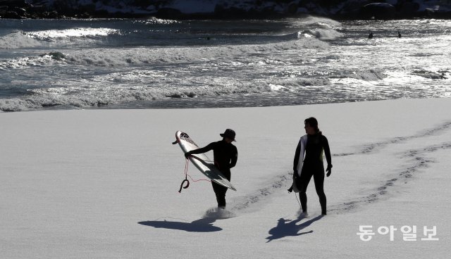 1일 강원 양양 죽도해변에서 서핑을 마친 서퍼들이 눈 덮인 해변을 걸어나오고 있다. 양회성 기자 yohan@donga.com