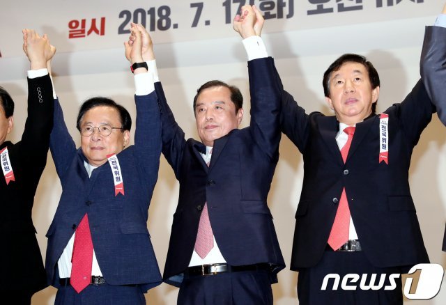 김성태 자유한국당 대표 권한대행 겸 원내대표와 김병준 신임 비상대책위원장, 이주영 국회부의장이지난해 7월 17일 오전 서울 여의도 국회 의원회관에서 열린 제2차 전국위원회에서 단상에 올라 손을 맞잡아 들고 있다. © News1