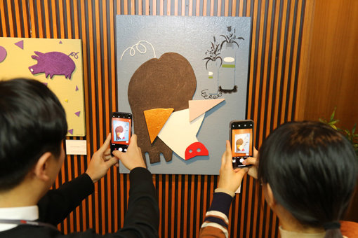 광동제약 직원들이 ‘2019 복 받으세요! 황금돼지 전(展)’ 작품을 감상하며 사진을 찍고 있다. 사진제공｜광동제약