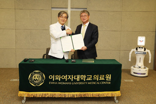 문병인 이화여자대학교 의무부총장 겸 의료원장(왼쪽)과 김덕준 로보케어 대표이사가 치매 환자의 로봇 인지훈련 기술 개발을 위한 업무협약 체결 후 기념촬영을 하고 있다. 사진제공｜이화의료원