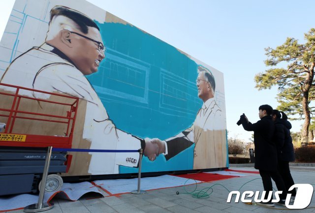 서울 종로구 청와대 인근 사랑채 앞에 설치중인 문재인 대통령과 김정은 북한 국무위원장이 악수하는 모습이 담긴 대형 미술작품을 시민들이 스마트폰 카메라에 담고 있다. 2018.12.7/뉴스1 © News1