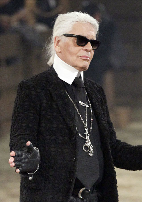 19일 향년 86세로 별세한 독일 출신의 패션디자이너 카를 라거펠트가 2013년 12월 미국 텍사스주 댈러스에서 열린 자신의 패션쇼 무대에 올랐을 때의 모습. 그는 뒤로 묶은 머리, 빳빳이 올려 세운 큼직한 셔츠 칼라, 검은색 선글라스, 손가락이 드러나는 가죽장갑으로 일관한 트레이드마크 차림새로도 유명했다. 댈러스=AP 뉴시스
