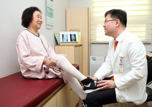 목동힘찬병원 남창현 원장이 무릎수술 환자의 재활을 돕는 신발인 ‘조인트슈즈’를 신겨주고 있다. 사진제공｜힘찬병원