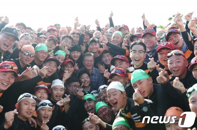 지난 2017년 경남 진해 공관에서 휴가중인 문재인 대통령이 해군사관학교 생도들의 전투수영 훈련 현장을 목격한 후 버스에서 내려 생도들을 격려한 후 기념촬영을 하고 있다. (청와대) 2017.8.4/뉴스1 © News1