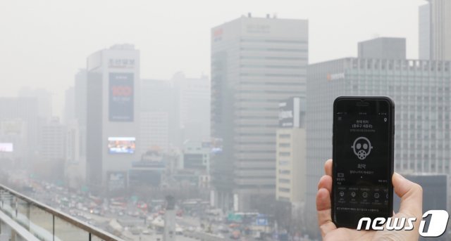 수도권에 닷새 연속 미세먼지 비상저감조치가 발령되는 등 관측 사상 최악의 고농도 미세먼지가 기승을 부린 5일 오후 서울 종로구 세종대로에서 미세먼지 상황을 알려주는 앱 화면 뒤로 도심이 뿌옇게 보인다. 2019.3.5/뉴스1 © News1