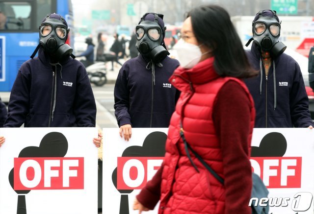 6일 오전 서울 광화문 광장에서 석탄발전 OFF 미세먼지 BYE 피켓 퍼포먼스를 펼치는 녹색연합 활동가들 앞으로 마스크를 쓴 한 시민이 지나고 있다.  2019.3.6/뉴스1 © News1