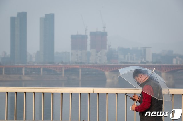 수도권 미세먼지 비상저감조치가 엿새째 이어지고 있는 6일 서울 동호대교 남단에서 마스크를 착용한 시민이 우산을 쓰고 걸어가고 있다. 2019.3.6/뉴스1 © News1