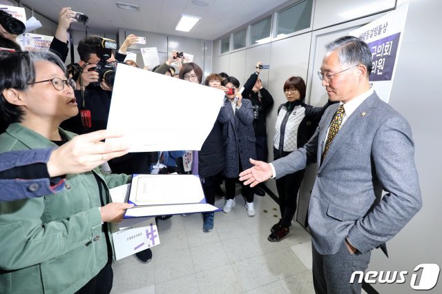 3.8세계여성의날 기념 제26회 대구여성대회 조직위원회 관계자들이 11일 오후 대구 중구의회를 방문해 홍준연 중구의원(오른쪽)에게 ‘2019 성평등걸림돌상’을 전달하자 홍 의원이 바지 주머니에 왼손을 넣은 채 나머지 한 손으로 상을 받고 있다. 대구여성대회 조직위원회 측에 따르면 홍준연 중구의원은 성매매집결지 자갈마당 폐쇄를 위한 정책입법 취지를 왜곡하고, 성매매여성에 대한 비하발언으로 혐오를 선동·조장했다는 이유로 성평등걸림돌상에 선정됐다. 2019.3.11/뉴스1 © News1