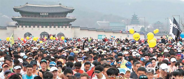 지난해 서울국제마라톤 겸 동아마라톤에서 참가자들이 출발 총성과 함께 광화문광장을 빠져나가고 있다. 마스터스들의 거대한 물결 위로 시간대를 적어 넣은 페이스메이커들의 노란 풍선이 보인다. 동아일보DB