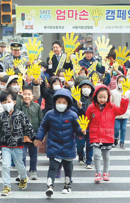 12일 오전 서울 서대문구 북가좌초등학교 앞에서 보행 안전을 위한 ‘엄마손 캠페인’에 참여한 어린이들이 횡단보도를 건너고 있다. 북가좌초교 학생인 이들은 노란색 손 모양 팻말을 엄마 손처럼 꼭 잡고 걸었다. 뉴시스