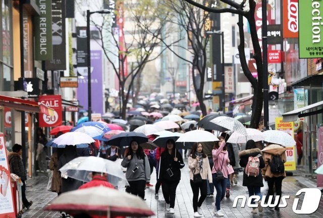 지난해 4월5일 서울 명동거리에서 외국인관광객들이 우산을 쓴 채 걷고 있다.  2018.4.5/뉴스1 © News1