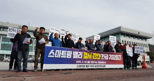 경남 농민단체 관계자들이 18일 오전 밀양시청 앞에서 기자회견을 갖고 있다. 이들은 ‘생산과잉 가격폭락 스마트팜 밸리 중단하라’는 구호를 외친 뒤 삼랑진읍까지 트럭 시위를 벌였다. 전농 부경연맹 제공