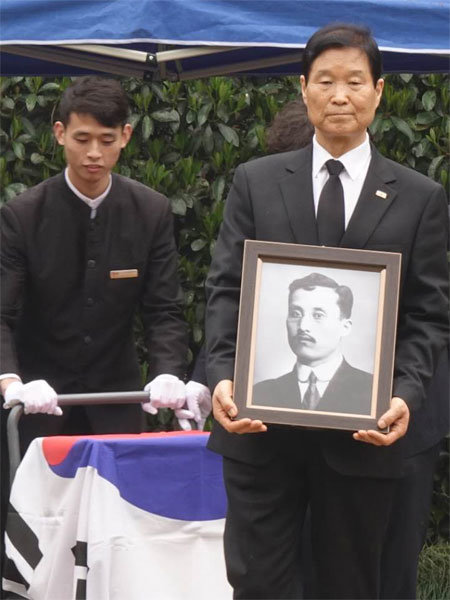 28일 중국 상하이 창닝구 묘지에서 열린 독립운동가 김태연 지사의 파묘 행사에서 외손자 조관길 씨(오른쪽)가 고인의 영정을 들고 있다. 주상하이 총영사관 제공