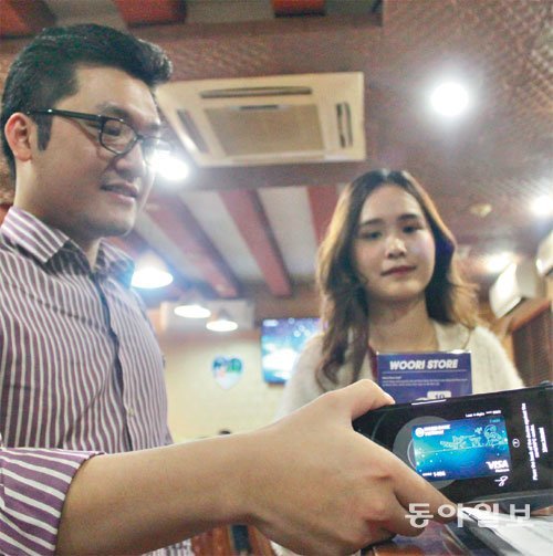 베트남 하노이의 한 음식점에서 손님이 스마트폰 앱에 뜬 ‘베트남우리은행 카드’로 음식값을 계산하고 있다. 하노이=조은아 기자 achim@donga.com