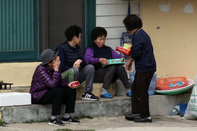 장천마을에서 한 주민이 이웃들에게 간식거리를 나눠주고 있다.