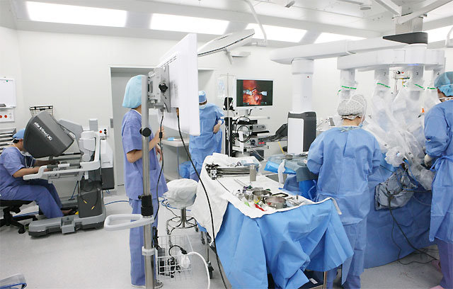 인하대병원 비뇨의학과 강동혁 교수(왼쪽에 앉은 사람)가 로봇 수술을 집도하고 있다. 오른쪽 누운 환자 몸에는 로봇 팔이 들어간 상태에서 강 교수가 콘솔(로봇 계기반)로 조종하고 있다. 인하대병원 제공