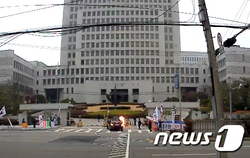 27일 오전 김명수 대법원장 출근길 차량이 대법원 정문 앞을 지날 때 한 남성이 화염병을 투척하고 있다. (김정수씨 제공)