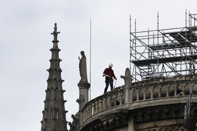 A workers walks on Notre Dame cathedral Wednesday, April 24, 2019 in Paris. Professional mountain climbers were hired to install synthetic, waterproof tarps over the gutted, exposed exterior of Notre Dame Cathedral, as authorities raced to prevent further damage ahead of storms that are rolling in toward Paris. (AP Photo/Thibault Camus)