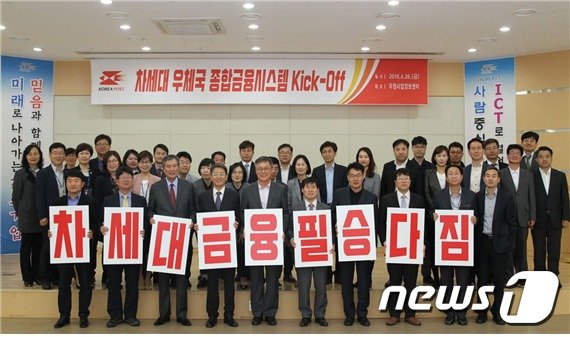차세대 우체국금융시스템 구축을 위한 킥오프가 4월 26일 전남 나주 우정사업정보센터에서 열려 강성주 우정사업본부장(앞줄 왼쪽에서 다섯 번째)과 참석자들이 프로젝트 성공의지를 담은 카드를 펼쳐보이며 단체사진을 촬영하고 있다© 뉴스1