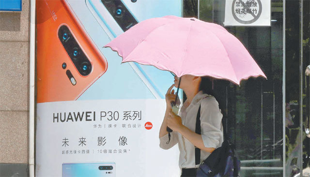 비상 걸린 화웨이 16일 중국 베이징에서 한 여성이 우산을 쓴 채 화웨이 스마트폰 광고판 앞을 지나가고 있다. 도널드 트럼프 미국 대통령은 전날 화웨이를 겨냥해 미국의 정보통신기술 및 서비스를 보호하기 위한 국가비상사태 선포 행정명령에 서명했다. 베이징=AP 뉴시스