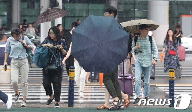 제주국제공항에서 공항 이용객들이 내리는 비를 맞으며 발걸음을 재촉하고 있다.2018.6.19/뉴스1 © News1
