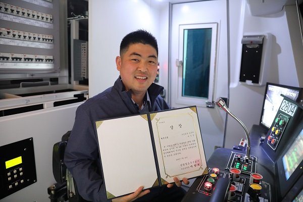 안내방송 경진대회 최우수상을 수상한 나인찬 기관사가 대회가 진행된 모의운전연습기에서 기념촬영을 하고 있다.