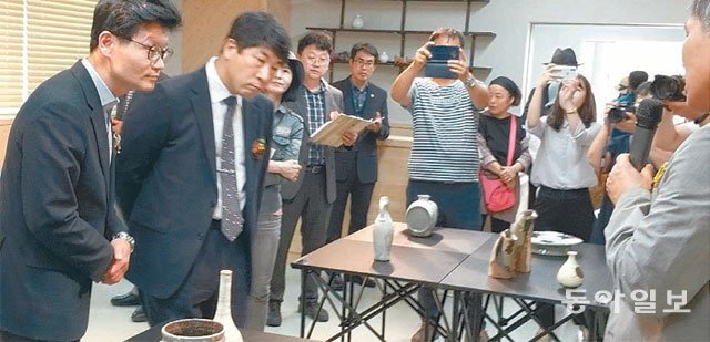 충남 공주시 계룡산도예촌에서 열리는 세계철화분청사기전 개막식에 참석한 김정섭 공주시장(왼쪽) 등이 철화분청사기에 대한 설명을 듣고 있다. 이기진 기자 doyoce@donga.com