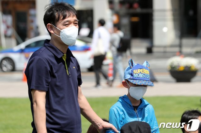 초미세먼지 농도가 ‘나쁨’을 보인 지난 5일 오후 서울광장에서 열린 ‘2019년 제 15회 어린이주간 및 제 97회 어린이날 아동권리 축제’에서 마스크를 쓴 어린이와 아버지가 행사를 지켜보고 있다. 2019.5.5/뉴스1 © News1