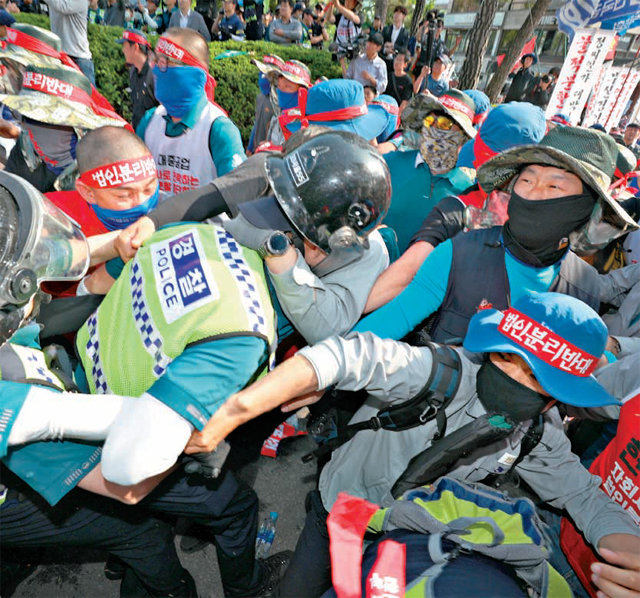 지난달 22일 서울 종로구 현대중공업 서울사무소 앞에서 열린 전국민주노동조합총연맹 금속노조 집회에서 한 경찰관이 집회 참가자들에게 둘러싸인 채 글려가고 있다. 뉴스1