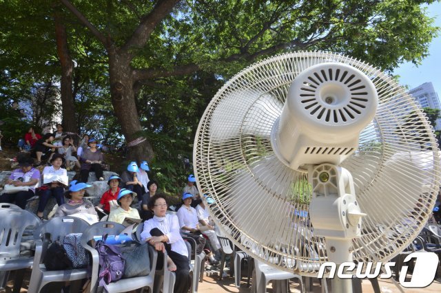 25일 오후 서울 강남구 봉은사에서 열린 전통문화체험관 준공식에서 참석자들이 땡볕을 피해 그늘에서 선풍기 바람을 쐬고 있다. 2017.7.25/뉴스1 © News1