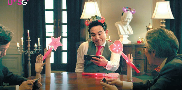‘손병호 게임’이 나오는 LG유플러스 5G 유튜브 동영상 광고의 한 장면. 코믹한 표정을 짓고 있는 배우 손병호 씨(가운데)가 스마트폰을 통해 LG유플러스 5G 서비스를 이용하고 있다. LG유플러스 제공