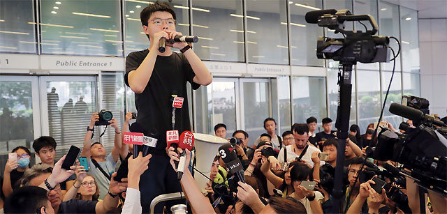 조기 석방된 ‘우산혁명’ 주역… 출소하자마자 시위 현장으로 17일 홍콩 입법회(의회) 인근에서 
2014년 홍콩 ‘우산혁명’의 주역인 학생운동가 조슈아 웡이 시위대와 취재진에 둘러싸여 연설하고 있다. 우산혁명 당시 법원의 시위
 해산 명령을 따르지 않은 혐의 등으로 수감됐던 웡은 이날 홍콩 당국에 의해 조기 출소했다. 그는 출소 직후 “범죄인 인도법 
개정안 반대 시위에 동참하겠다”고 밝혔다. 홍콩=AP 뉴시스