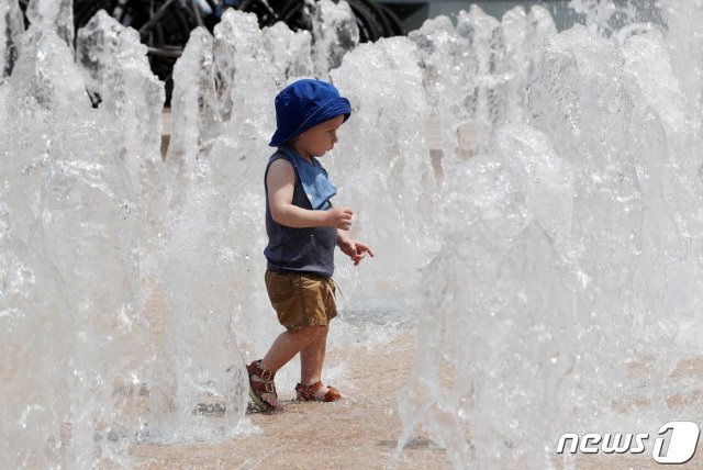 서울 낮 기온이 27도까지 오르며 무더운 날씨를 보인 12일 오전 서울 중구 서울광장 분수대에서 한 어린이가 더위를 식히고 있다. © News1