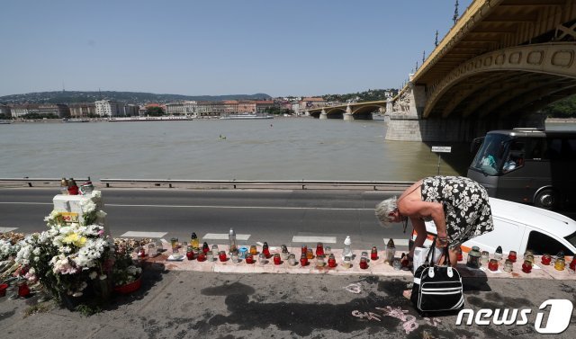 13일(현지시간) 헝가리 부다페스트 다뉴브강 머르기트 다리 유람선 ‘허블레아니호’ 침몰현장 인근에 마련된 유람선 사고 희생자 추모공간에서 한 헝가리 시민이 추모객들이 남긴 초와 꽃을 정돈하고 있다. 2019.6.13/뉴스1