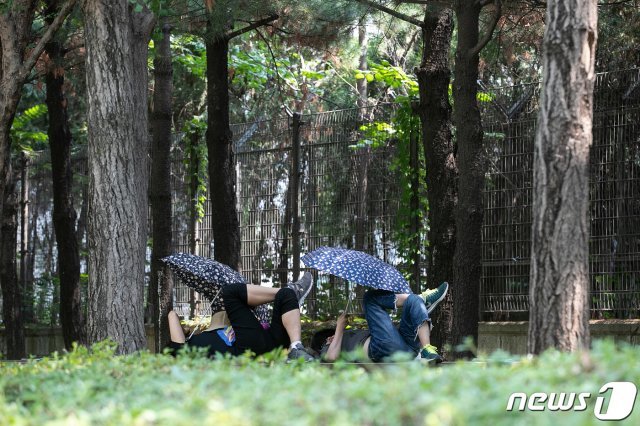 전국적으로 30도 안팎의 기온을 보이는 24일 오후 서울 성동구 서울숲을 찾은 시민들이 나무 그늘 아래서 더위를 식히고 있다. © News1