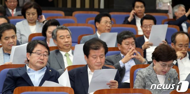 자유한국당 의원들이 24일 서울 여의도 국회에서 열린 의원총회에서 여야 국회 정상화 합의문을 보고 있다.  © News1